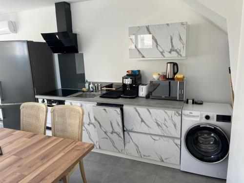 une cuisine avec lave-linge et sèche-linge à côté d'une table dans l'établissement Maison10 avec 1 chambre lechaffardcom, à Satolas-et-Bonce