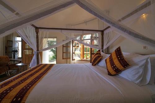 a bedroom with a large white bed with pillows at Lake George View Golf Resort in Kahendero