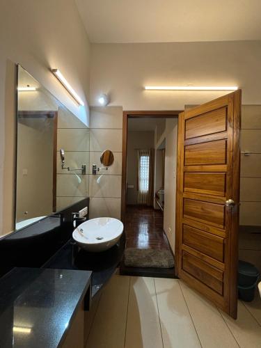 a bathroom with a sink and a wooden door at Barefoot Homes, Varkala in Varkala