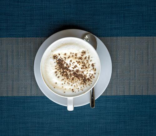 a cup of coffee with a spoon on a table at Lake George View Golf Resort in Kahendero