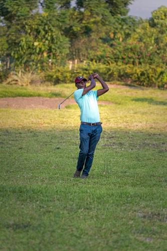 a man swinging a golf club in a field at Lake George View Golf Resort in Kahendero