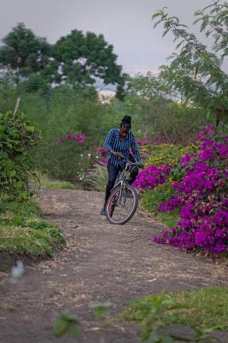 a man riding a bike on a path with flowers at Lake George View Golf Resort in Kahendero