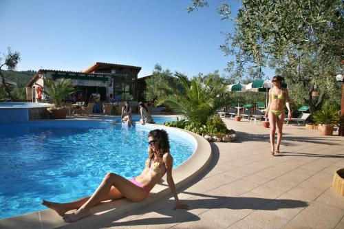 a woman in a bikini sitting next to a swimming pool at Tenuta Padre Pio in Vieste