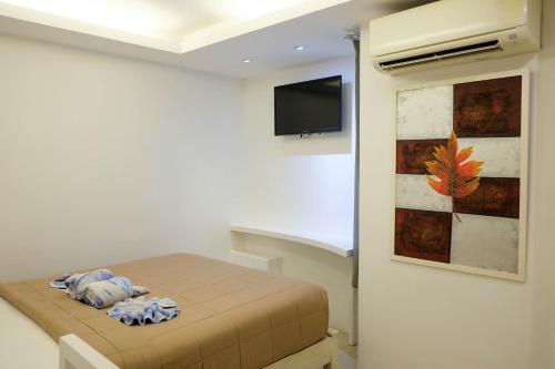 a small bedroom with a bed and a tv at Baanpoon Apartment in Chaweng