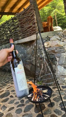 una persona sosteniendo una botella de vino sobre el fuego en Villa Belegu Mountain, en Deçan