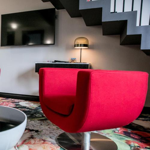 a red chair in a living room with a table at Amsterdam Plaza Hotel & SPA in Palanga