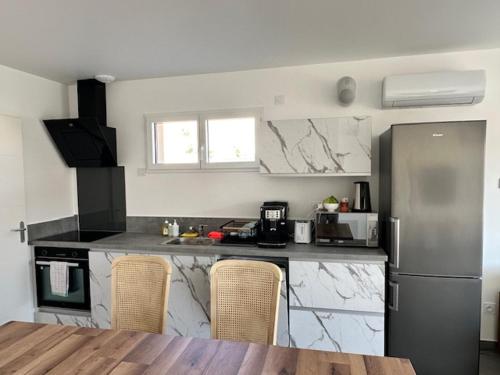 - une cuisine avec des comptoirs en marbre et un réfrigérateur dans l'établissement Maison 50 avec 5 chambres lechaffardcom, à Satolas-et-Bonce