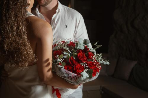 a bride and groom holding a bouquet of red roses at Aegean Castle Andros – Adults Only in Agia Eleousa