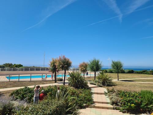 2 personnes debout dans un parc près d'une piscine dans l'établissement Apt 4 personnes, Résidence Atoll, piscine & vue sur la mer, à Les Sables-dʼOlonne