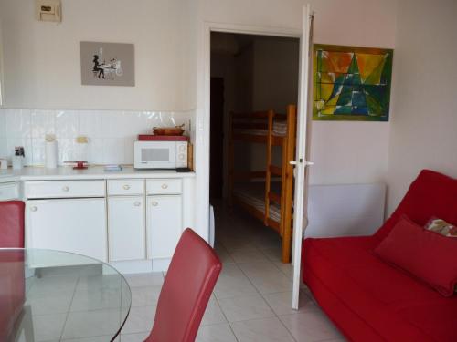 Il comprend une cuisine équipée d'un fauteuil rouge et d'un four micro-ondes. dans l'établissement Apt 4 personnes, Résidence Atoll, piscine & vue sur la mer, à Les Sables-dʼOlonne