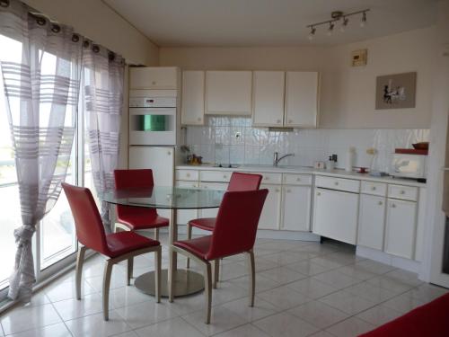 une cuisine avec une table en verre et des chaises rouges dans l'établissement Apt 4 personnes, Résidence Atoll, piscine & vue sur la mer, à Les Sables-dʼOlonne