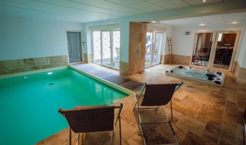 a swimming pool with two chairs in a house at Les Gîtes de Sprimont - Le Cosy in Sprimont