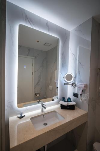 a bathroom with a sink and a large mirror at Holiday Hotel in Tirana