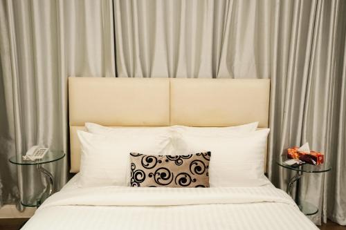 a white bed with a black and white pillow on it at Royal Residence Dhaka in Dhaka