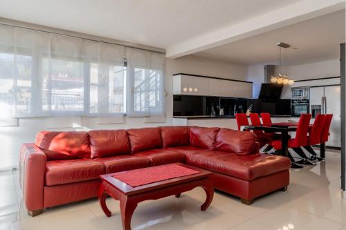 a living room with a red leather couch and a table at Vila Blanka in Podgora