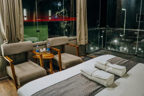 a bedroom with a bed and two chairs and a window at Harmony Heights in Mukteswar