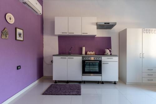 a kitchen with white cabinets and purple walls at Vila Blanka in Podgora