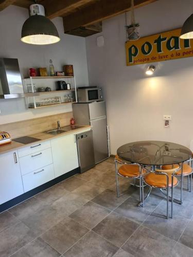 une cuisine avec une table et des chaises en verre ainsi qu'un comptoir dans l'établissement Gîtes Le Séchoir, à Saint-Dié-des-Vosges