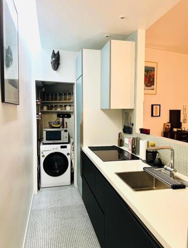 - une cuisine équipée d'un lave-linge, d'un évier et d'une cuisinière dans l'établissement Appartement d'Architecte chic et élegant, à Paris