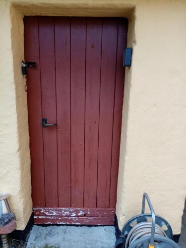 a red door of a building with a cart in front at Hytten in Frøstrup