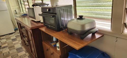 a room with a table with a microwave and a television at Meyenburg Units in Mount Morgan