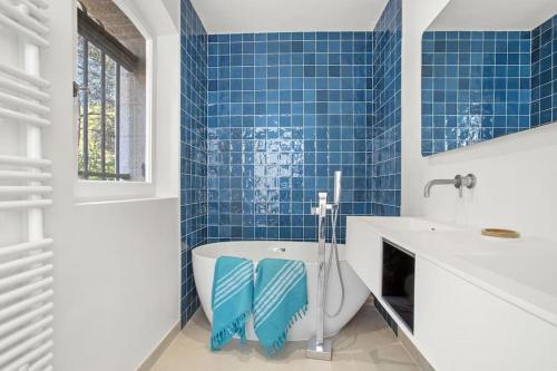 La salle de bains est pourvue de carrelage bleu, d'une baignoire et d'un lavabo. dans l'établissement Villa, 8 pers, pieds dans l'eau, à Saint-Raphaël