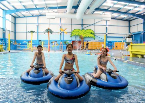 three girls are riding on rides in a swimming pool at Golden Palm Resort in Chapel Saint Leonards