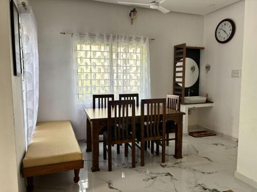 a dining room with a table and chairs and a clock at Ayurville Homestay in Cochin