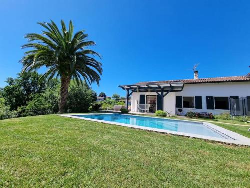 une villa avec un palmier et une piscine dans l'établissement Maison avec piscine et terrain de pétanque, à Urrugne