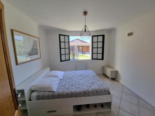 une chambre avec un lit et deux fenêtres dans l'établissement Maison avec piscine et terrain de pétanque, à Urrugne