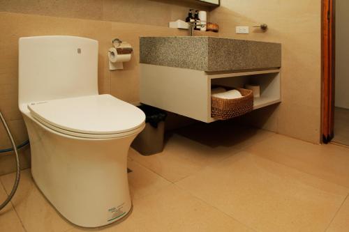 a bathroom with a white toilet and a sink at The Spring House in Irosin
