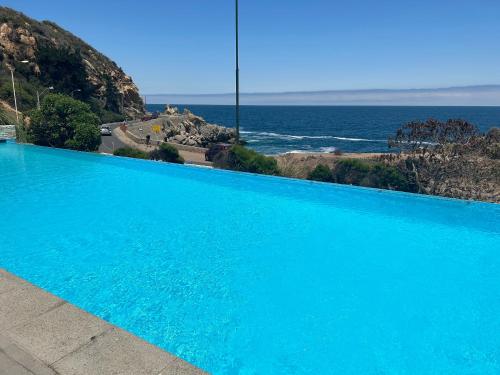 a large blue swimming pool next to the ocean at Una vista increíble al Pacifico in Concón
