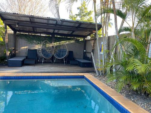 a swimming pool with chairs and a pergola next to a house at Cool Cabana Mermaid Beach in Gold Coast