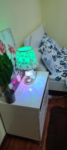a table with a lamp on it next to a bed at Home Away Apartment in Abu Dhabi