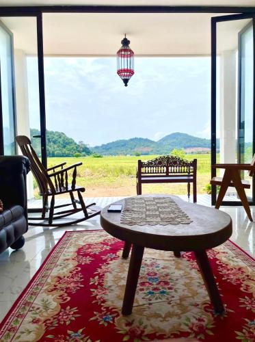 a living room with a table and a large window at Villa Kamila in Mersing