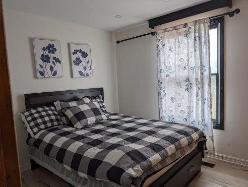 a bedroom with a black and white bed and a window at Peaceful and Heavenly Private Water Front Cottage on 100 Acres of Scenic Beauty- Trent Lakes in Kinmount