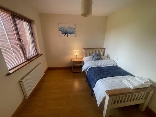 ein Schlafzimmer mit einem Bett mit einer blauen Decke in der Unterkunft 3 Bedroom House 03 In Famous Esker Hills Golf Resort in Tullamore