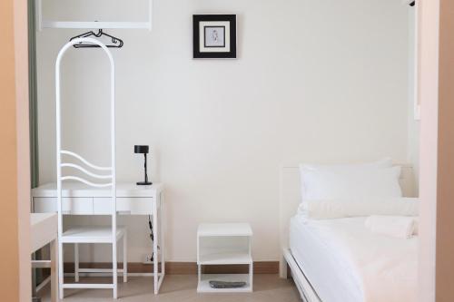 a white bedroom with a bed and a desk at ResT Bangkok Poshtel in Bangkok