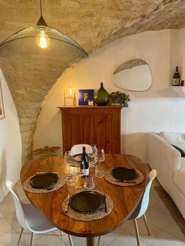 - une table en bois avec des chaises et des verres à vin dans l'établissement Charmante maison de village au pied du Lùberon, à Cabrières-dʼAigues