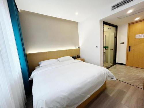 a bedroom with a large white bed and a bathroom at Yuyuan Hotel Xuancheng Guogou Plaza in Xuancheng