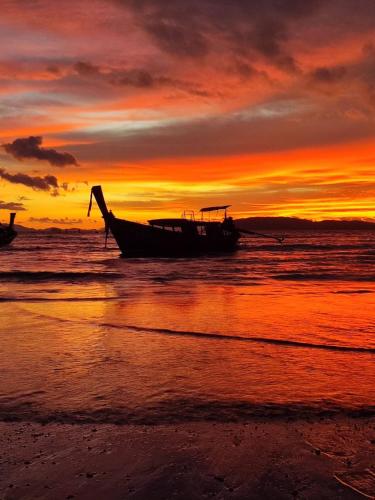 a boat sitting on the beach at sunset at "Smooth as Silk" Gorgeous 3-Bedroom Pool Villa, Just a Stone's Throw from the Beach! in Ban Khlong Haeng