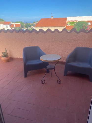 two blue chairs and a table on a patio at Chambre tout confort in Saint-Nazaire