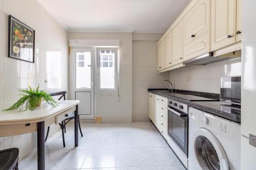 a kitchen with white cabinets and a washer and dryer at Apartamentos Asturias Holidays by Gestión House in Noreña