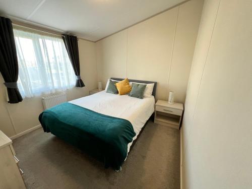 a bedroom with a bed with a green blanket at 2 Bedroom Lodge, OG30, Shanklin, Isle of Wight in Shanklin