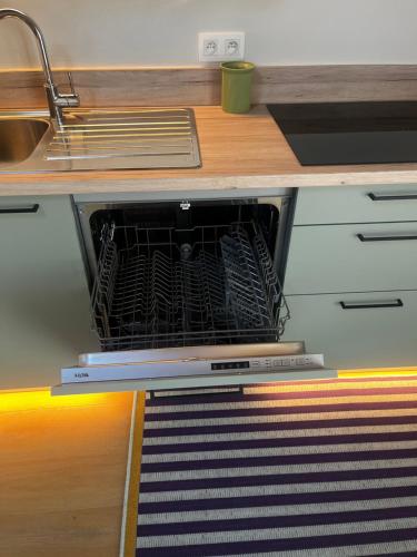 an open dishwasher in a kitchen under a counter at Appartement ' Studio Stockholm' in Geel