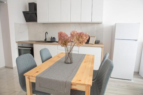 a kitchen with a wooden table with a vase of flowers on it at Apartamenty Ogrodowa in Zielona Góra