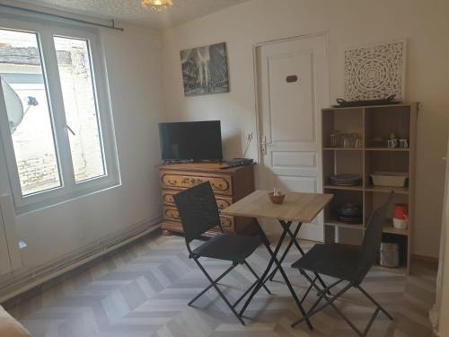 une pièce avec une table, des chaises et une télévision dans l'établissement Petit Studio Centre Cambrai, à Cambrai