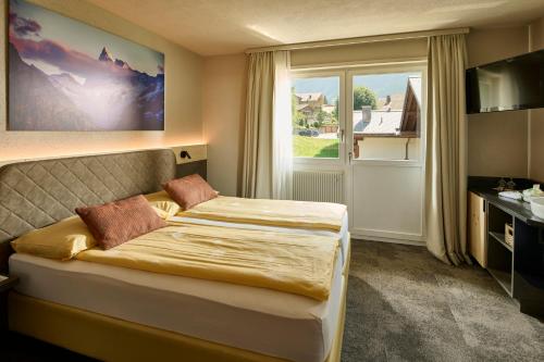 a hotel room with a bed and a window at Hotel Central Wolter - Grindelwald in Grindelwald