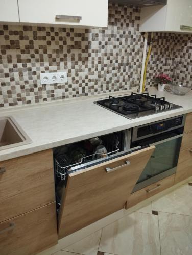a kitchen with a stove and an open dishwasher at Comfortable apartment in the center of Ungheni in Ungheni