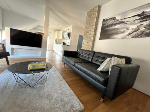 a living room with a black couch and a table at Loft Appartement Seven in Friedrichshafen